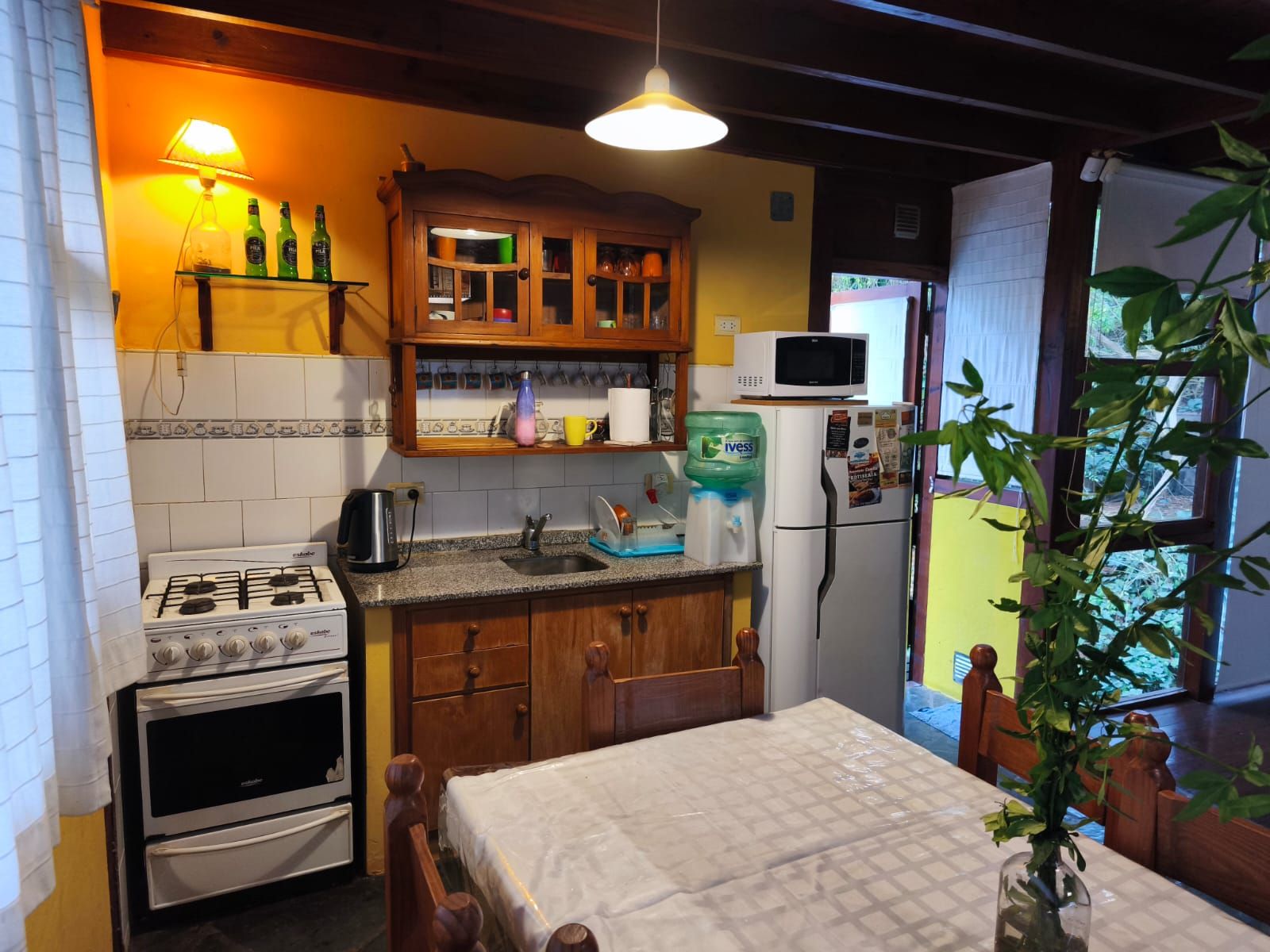 Cocina completa con mesada de granito, anafe, heladera y una alacena antigua de madera.