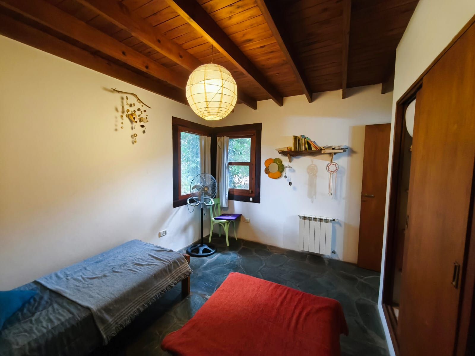 El segundo dormitorio armado con una cama de plaza y media y una cama baja, mantas tejidas y lámpara de papel.