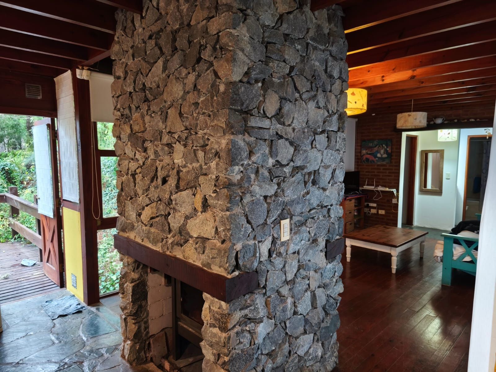 Detalle de la salamandra de piedra doble frente, con la puerta abierta al deck a un costado.